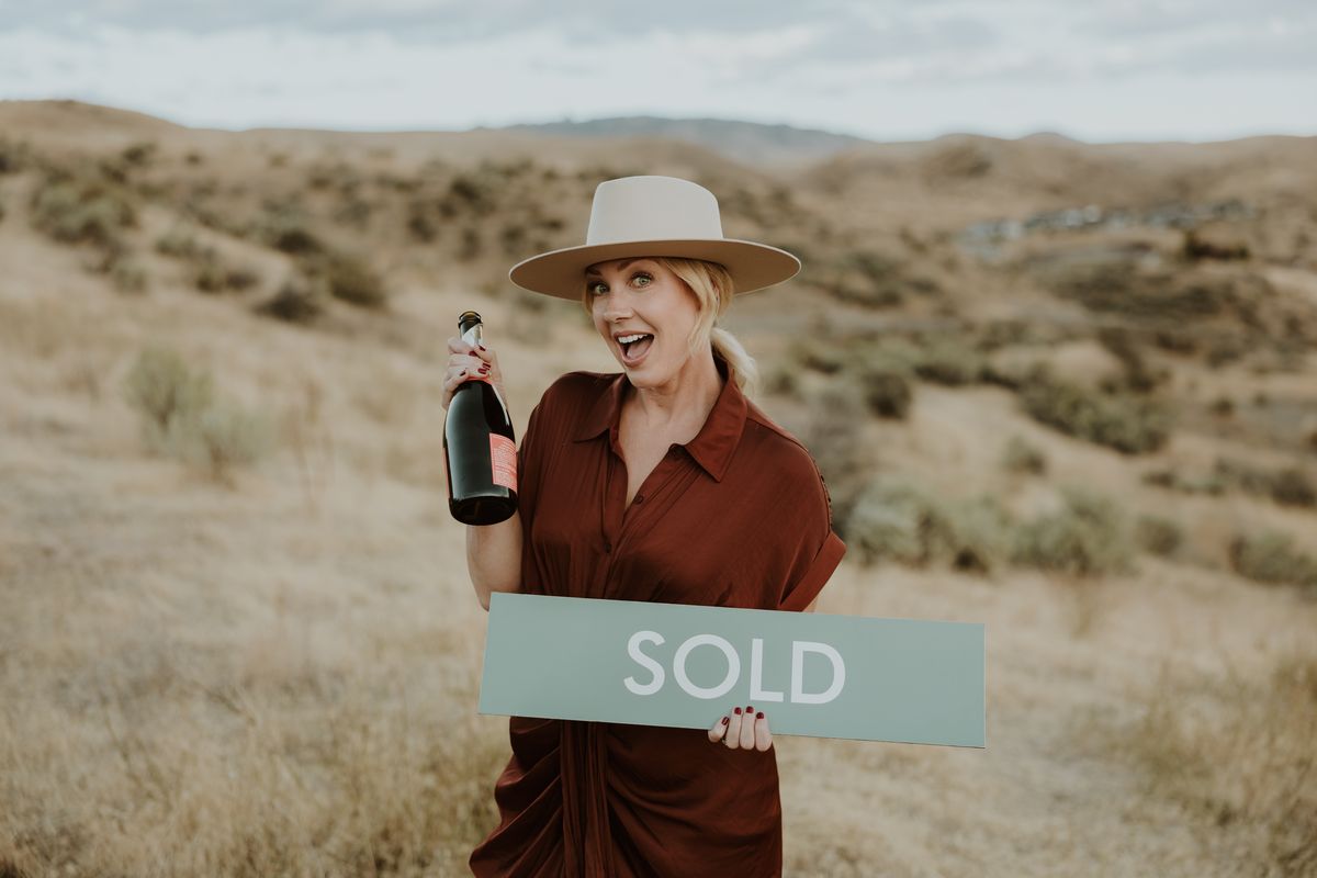 Kimberly Holland holding a SOLD sign in the foothills